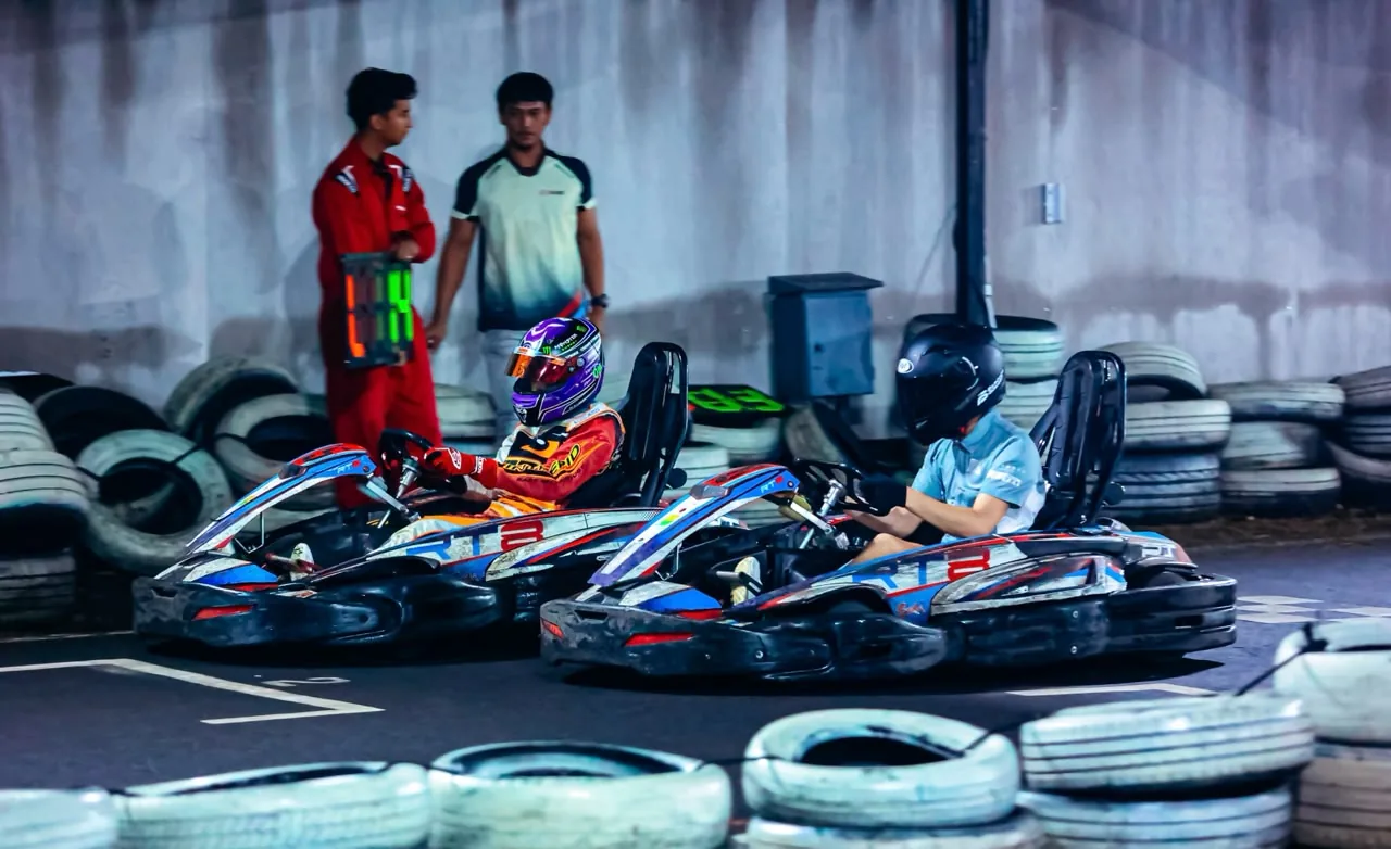 Two karts side by side with two team members standing behind